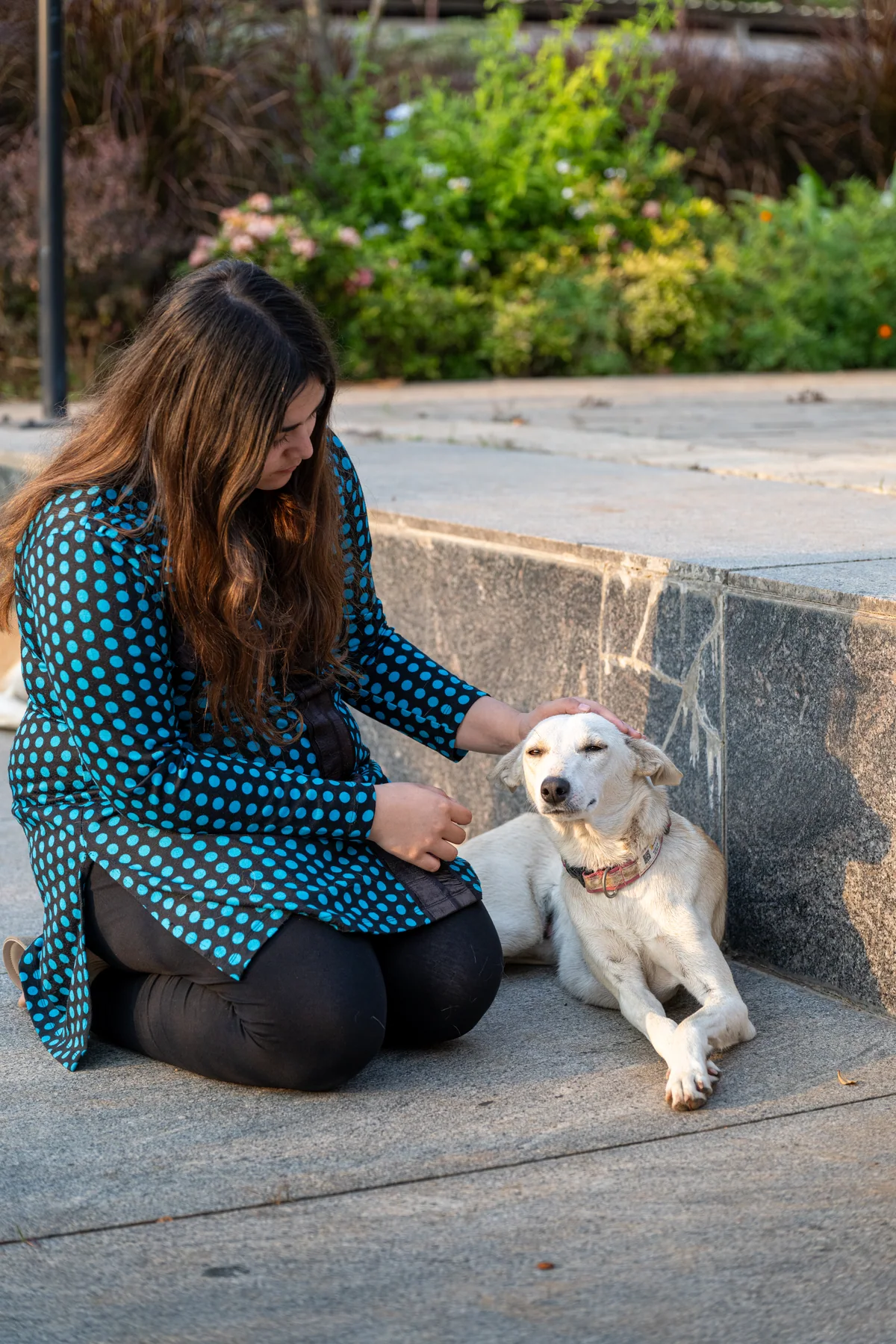 A community member sitting beside a white dog outdoors